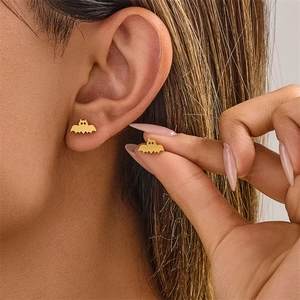 Gros plan de boucles d'oreilles chauve-souris dorées pour Halloween et style gothique