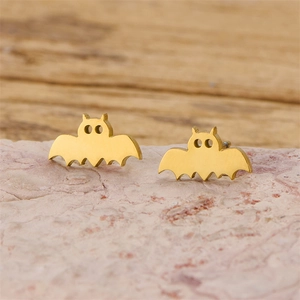 Gros plan de boucles d'oreilles chauve-souris dorées sur une pierre naturelle rose