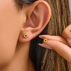Mini vintage gear earrings in gold stainless steel worn on ear for industrial style