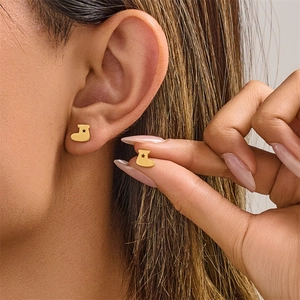 Macro detail of gold Christmas stocking stud earrings with star cutouts on ears