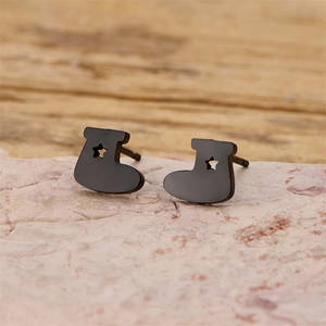 Close-up of black boot-shaped earrings with star cutout on a pink stone background