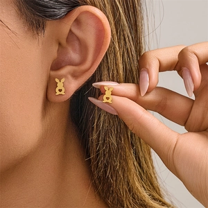 Close-up of heart-cutout rabbit stud earrings in gold finish worn by a female model