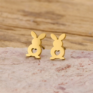 Detailed view of gold rabbit stud earrings with heart cutout on a natural stone base