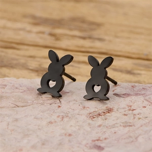 Detail of matte black rabbit stud earrings with heart cutout on natural stone