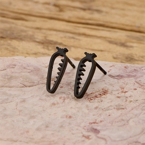 Macro de boucles d'oreilles carottes noires ajourées sur une pierre rose naturelle