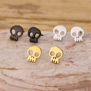 Gothic skull stud earrings set in gold, silver and black finishes on stone background