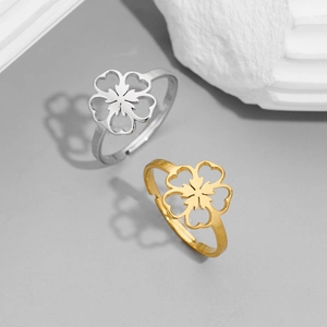 Close-up of cutout cherry blossom rings in gold and silver on a textured stone