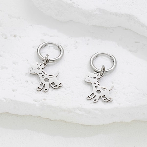 Minimalist silver giraffe cut-out drop earrings displayed on natural white stone base