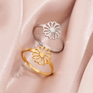 Polished hollow daisy flower rings in gold and silver on pink silk background
