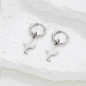 Polished silver stainless steel hoop earrings with minimalist star charms on stone background