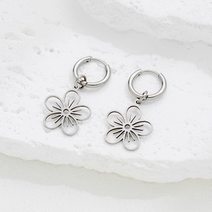 Bohemian stainless steel dangle earrings with hollow flower pendant on stone surface