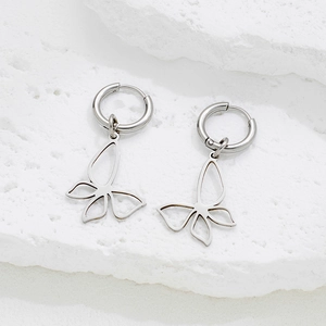 Boucles d'oreilles en acier inoxydable avec pendentif papillon sur un fond de pierre