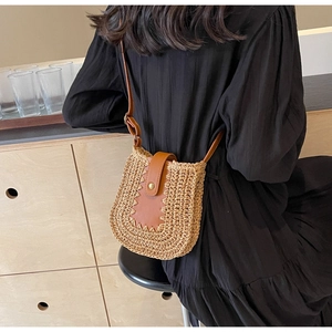 Sac bandoulière en paille avec rabat en cuir marron et boucle porté par un modèle
