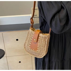Détail du sac bandoulière en paille tissée avec rabat en cuir marron et fermoir aimanté
