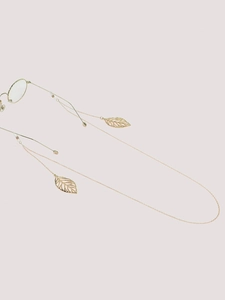 Detailed view of golden metal eyewear chain with elegant hollow leaf pendants on pink