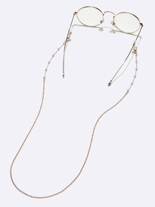 Detailed view of elegant gold eyeglass chain with white pearls on a white background