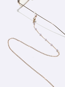 Close-up of gold glasses chain with pearls and silicone loops on white background