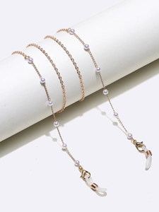 Close-up of golden pearl eyewear chain with silicone loops on a white cylinder stand