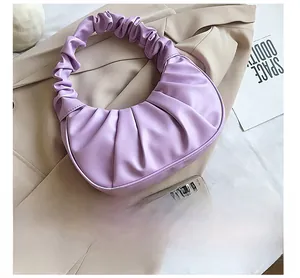 Detail view of purple ruched cloud bag on a blazer next to a smartphone for size reference