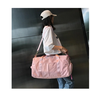 Pink gym bag with side compartment for shoes and adjustable strap shown on model