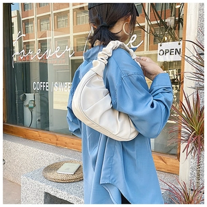 Close-up of beige ruched cloud hobo bag with pleated shoulder strap detail