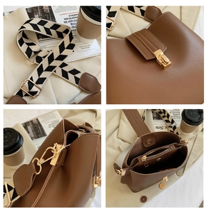 Detail of caramel brown bucket bag with woven strap and golden metal hardware