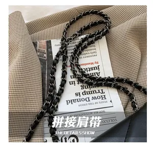 Detail of a chic black leather woven silver chain shoulder strap on a tote bag