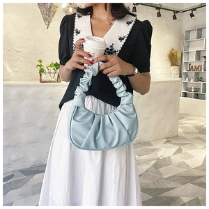 Light blue pleated faux leather shoulder bag shown in a stylish lifestyle setting