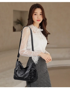 Model wearing a black soft leather shoulder bag with multi-zipper detail in casual style