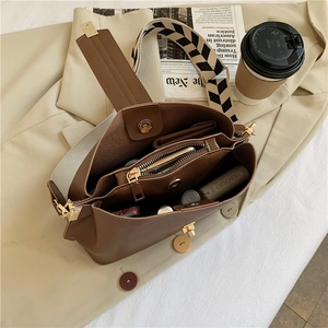 Interior detail of a brown leather bucket bag with wide strap and multiple pockets