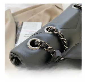 Detail of metal grommets and chain strap with black satin bow on leather tote bag
