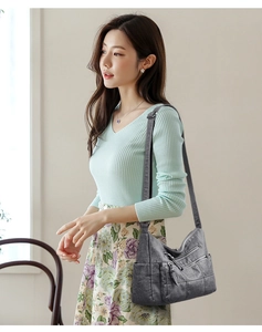 Grey soft leather shoulder bag with multiple zippers shown on a model in a casual outfit