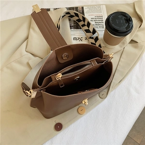 Detail view of brown shoulder bag interior compartments and patterned wide strap