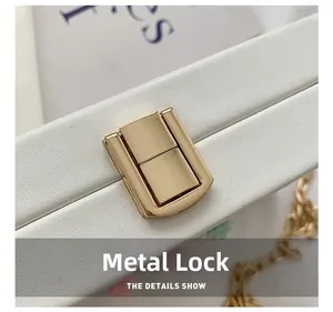 Makroaufnahme des goldenen Drehverschlusses und der Kette auf der weißen Ledertasche