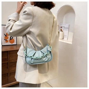 Close-up of mint blue pleated cloud bag with chunky acrylic chain and gold strap detail