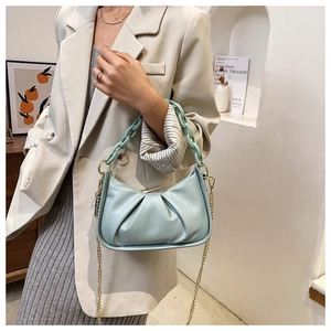 Detail of light blue pleated cloud bag with acrylic chain strap and gold shoulder link