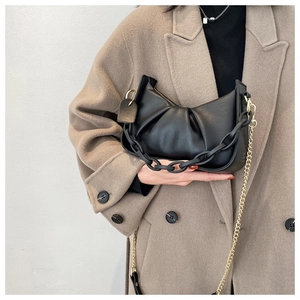 Detail view of black ruched cloud bag featuring acrylic chain and gold metal strap