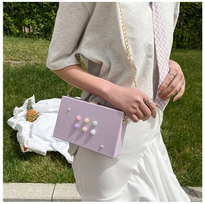 Detail der fliederfarbenen Box-Tasche mit 3D-Blumen und goldener Kettenriemen