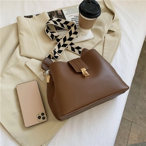 Detail of dark brown bucket bag with a chic black and white herringbone wide strap