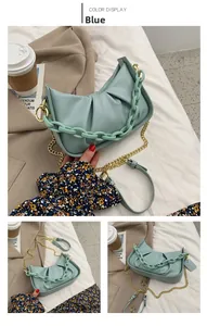 Detail of light blue pleated cloud bag with chunky acrylic chain and gold metal strap