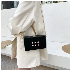 Detail einer schwarzen Box-Tasche mit bunten Kamelienblüten und Perlenverzierungen