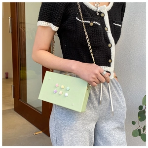 Hellgrüne Box-Tasche mit bunten 3D-Blumen und goldener Kette an einem Modell gezeigt