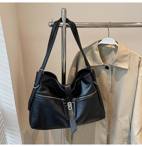 Détail du sac hobo en similicuir noir avec fermoir métallique et détails de fermetures éclair