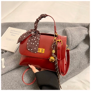 Detail of burgundy leather crossbody bag with vintage gold twist lock and silk scarf handle