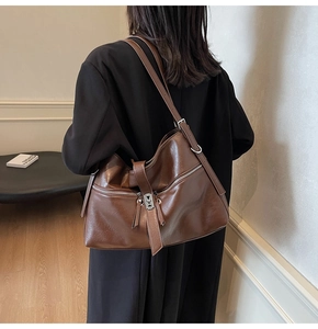 Détail du sac hobo en cuir marron foncé avec deux poches zippées et boucle argentée