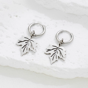 Silver stainless steel maple leaf drop hoop earrings on white stone background
