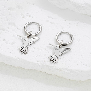 Polished silver hummingbird hoop earrings with detailed bird pendants on stone surface