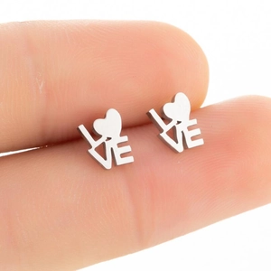 Detailed close-up of heart-shaped stainless steel stud earring with LOVE engraving on fingertip