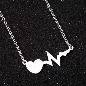 Collana minimalista argentata con ciondolo battito cardiaco su sfondo nero scintillante