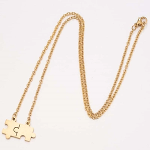 Detailed macro view of 18K gold puzzle pendant on a stainless steel chain necklace